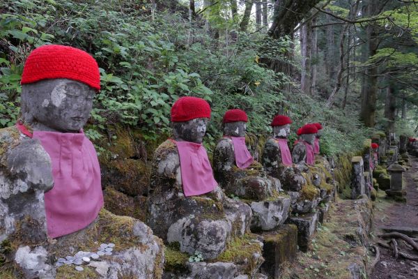 Sochy Jizo s červenými čepičkami a bryndáky.