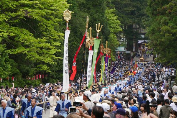 Od Toshogu se v průvodu nesou vysoké vlajky a prapory.